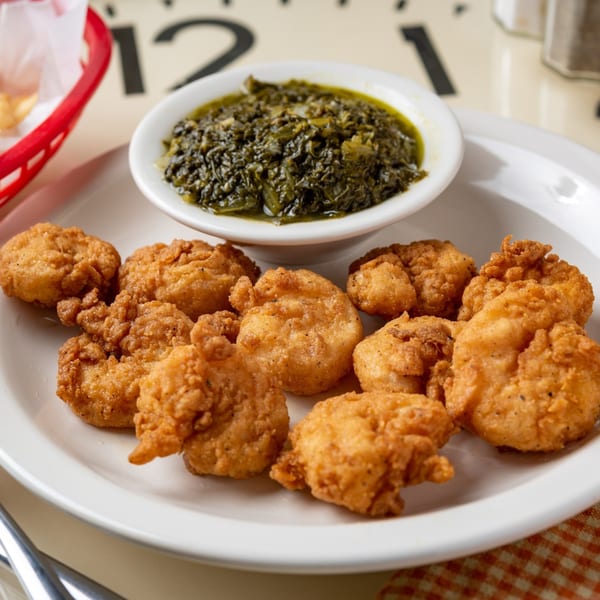 Fried shrimp and a side of collard greens on a white plate at Time To Eat Cafe.